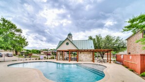 A swimming pool with a gazebo, a brick building, and a fenced area.