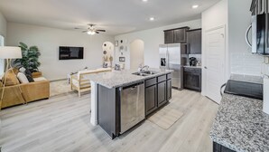 A modern kitchen with a central island, stainless steel appliances, and a dining area with a sofa and chairs.