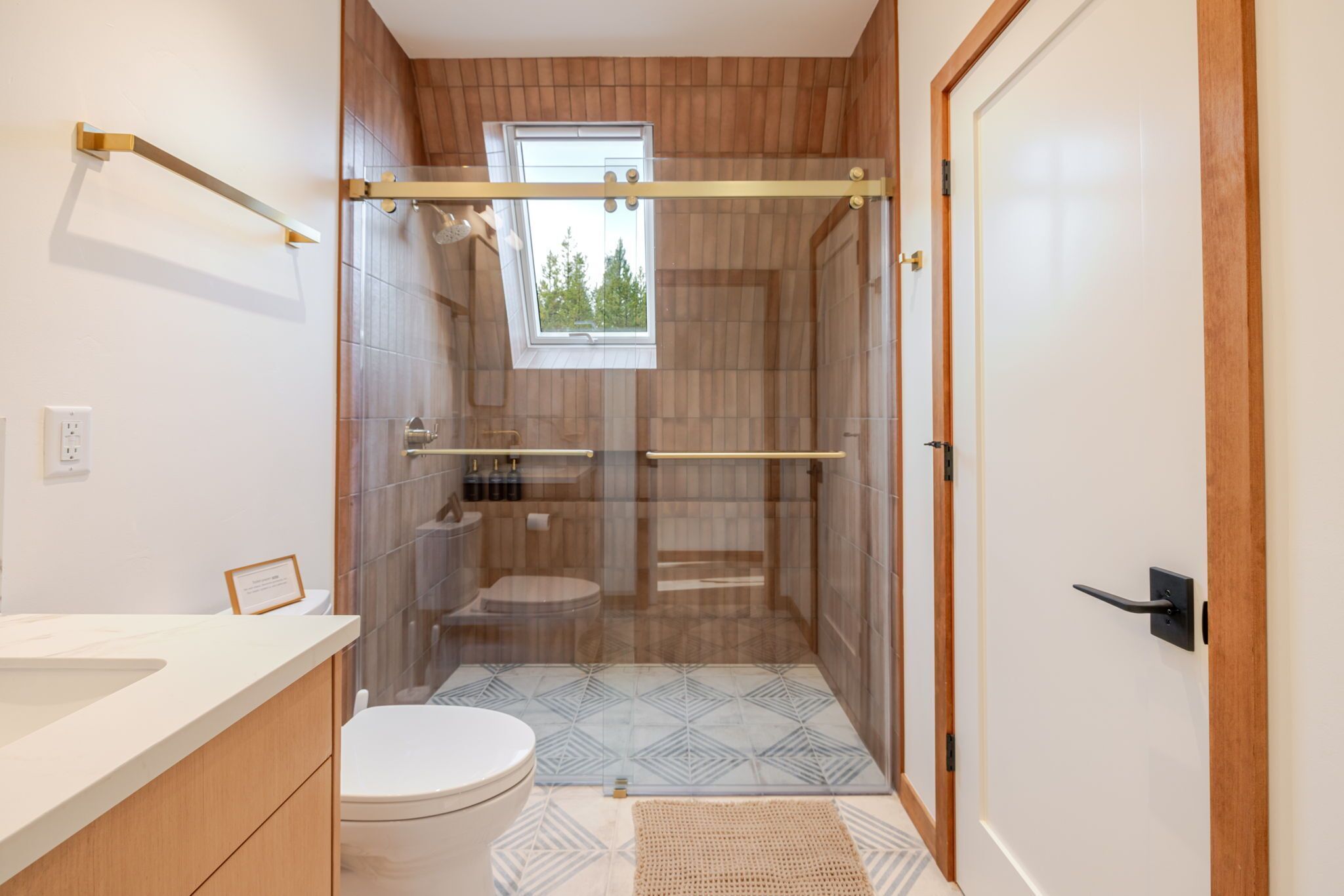 A modern bathroom with a glass-enclosed shower, a toilet, and a sink with a wooden vanity.