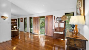 Una habitación amplia con piso de madera, un banco de madera, una lámpara y un cuadro en la pared.
