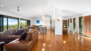 Un espacio habitable amplio con un sofá de cuero marrón grande, una mesa de comedor y una cocina al fondo.