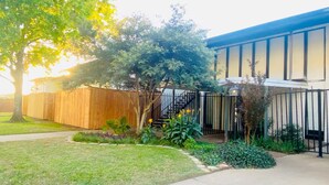 A modern building with a wooden fence, a paved pathway, and various plants.