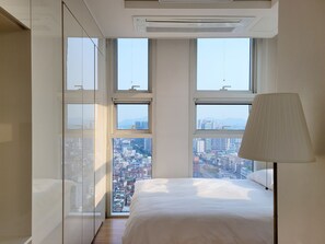A bedroom with a bed, a lamp, and large windows offering a city view. - [Seoul Station]Panorama Skyline  – Nice View & Free Gym (Seoul)