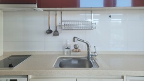 Una cocina con un lavamanos de acero inoxidable, un dispensador de jabón para platos y una rejilla metálica sobre el lavamanos.