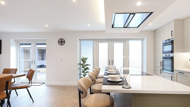 A modern kitchen with a central island, built-in ovens, and a skylight. - Stylish modern home with games room, luxury kitchen and two en suite bedrooms. (Ross-on-Wye)