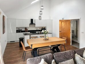 Eine moderne Küche mit weißen Schränken, einem schwarzen Herd und einem Holzespeisesaal mit Stühlen.