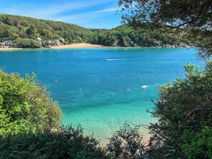 Un paysage côtier caractérisé par une eau turquoise cristalline, une plage de sable et une végétation luxuriante.