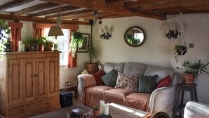 Ein gemütliches Wohnzimmer mit einer Holzsofa, einem Couchtisch und verschiedenen Pflanzen.