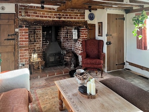A cozy room with a brick fireplace, a red armchair, and a wooden table with candles.