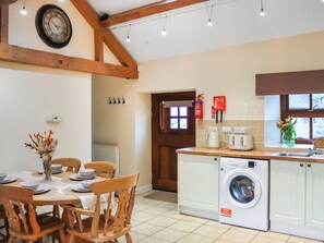 Une cuisine équipée d’un lave-linge, d’une table à manger avec des chaises, d’une horloge et d’un extincteur.