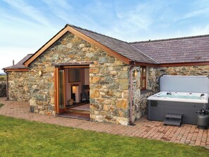 Un bâtiment en pierre doté d’un jacuzzi et d’une porte donnant accès à l’intérieur.