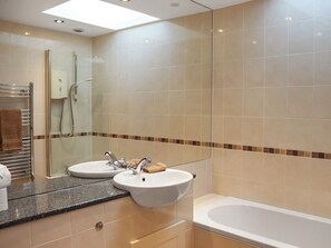 Une salle de bain moderne avec deux lavabos, une baignoire et une douche à l’italienne.