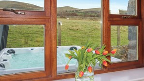 A window with a view of a hot tub and a vase with tulips. - Beudy Newydd - UK50959 (Llanllechid, near Bangor)