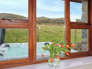 Une fenêtre donnant sur un jacuzzi et un vase rempli de tulipes.