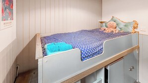 Ein Etagenbett mit blauer Matratze mit Sternenmuster, einer blauen Decke und einem Kuscheltier. Darunter befinden sich zwei Schubladen.