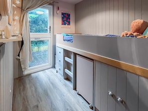 A compact kitchen with a window, a poster on the wall, and a teddy bear on the counter. - A lovely lodge in a great holiday village. (Kingsdown, Deal)