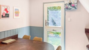 Ein Essbereich mit einem runden Tisch, vier Stühlen und einem Fenster mit Blick auf Grünflächen.