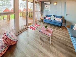 A cozy living room with a blue sofa, a wooden coffee table, and a colorful cushion. - A lovely lodge in a great holiday village. (Kingsdown, Deal)