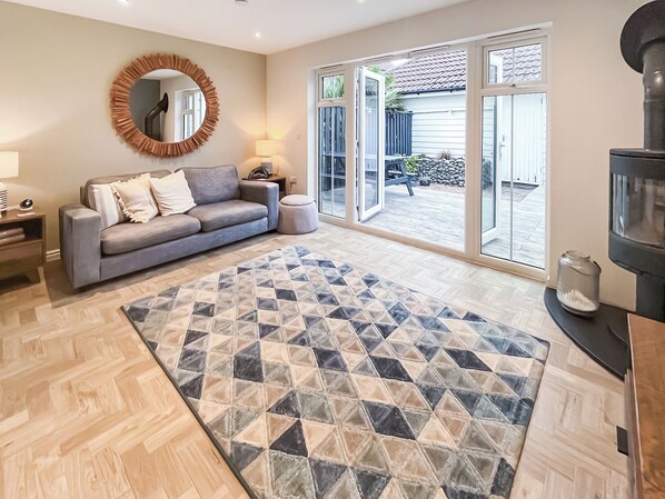 A living room with a sofa, a patterned rug, a round mirror, and a television. - 2 bedroom accommodation in Rye (Rye)