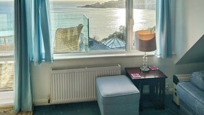 Une chambre avec vue sur la mer, un radiateur, une lampe et une petite table avec une chaise.