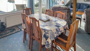 Un espace repas comprenant une table, des chaises et donnant sur un plan d’eau.