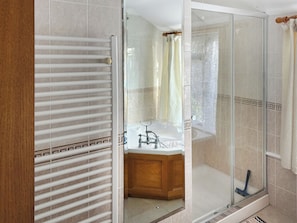 A bathroom with a glass shower enclosure, a wooden vanity, and a bathtub. - 1 bedroom accommodation in Coverack (Coverack)