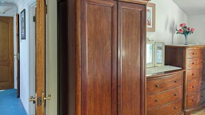 Une pièce comprenant une armoire en bois, une commode avec des tiroirs et un miroir placé sur la commode.
