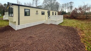 A single-story mobile home with a covered porch and a small deck.