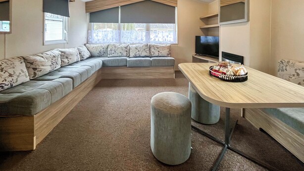 A compact living space with a sofa, a dining table, a television, and a window with blinds.