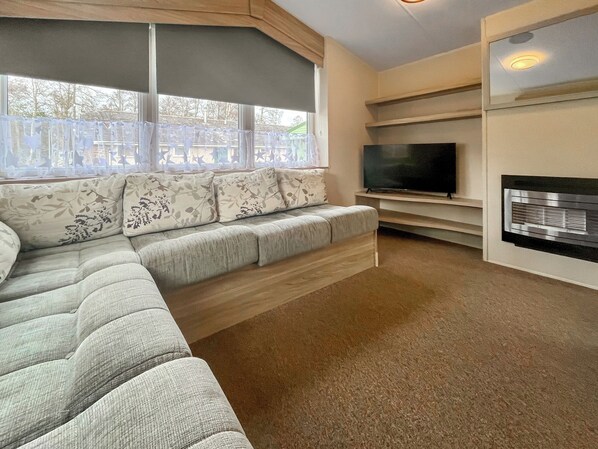 A modern living room with a sectional sofa, a flat-screen TV, and a built-in fireplace.