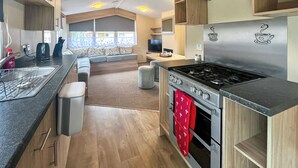 A modern kitchen with a gas stove, oven, and a seating area with a view.