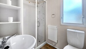 A bathroom with a white sink, toilet, and glass shower enclosure.