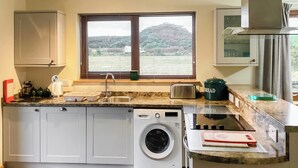 A compact kitchen with a washing machine, a toaster, and a bread container. - 4 bedroom accommodation in Brora (Brora)
