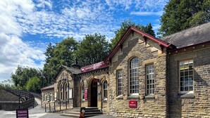 A stone building with a sign reading 'Haworth Station' and a 'No Parking' sign. - Mini Goose cottage - UKC7088 (Laycock)