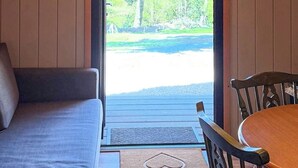 A room with a sofa, a wooden table, and a view of a green landscape through a glass door. - The Orchard - UKC7804 (Shrewsbury)