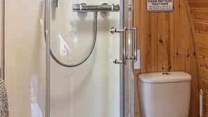 A wooden bathroom with a glass shower enclosure, a toilet, and a sign instructing to flush toilet paper only. - The Orchard - UKC7804 (Shrewsbury)
