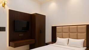 A modern bedroom with a large bed, built-in TV, and a wooden wardrobe. - Hotel Empress Grand, 2.5km from Taj Mahal (Agra)