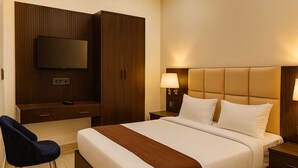 A modern hotel room with a large bed, a flat-screen TV mounted on the wall, a desk with a chair, and a nightstand with lamps. - Hotel Empress Grand, 2.5km from Taj Mahal (Agra)