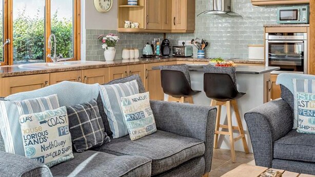 Een gezellige keuken met houten kastjes, een vast aanrecht en een eethoek met twee stoelen.