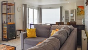 En moderne stue med en grå sofa, et træbord og en sort metalkasse til opbevaring.
