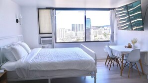 Habitación de hotel con cama, escritorio y silla. Ventana con vista a la ciudad.