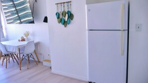 Una cocina moderna con un refrigerador blanco, una mesa de comedor con sillas y un adorno en la pared.