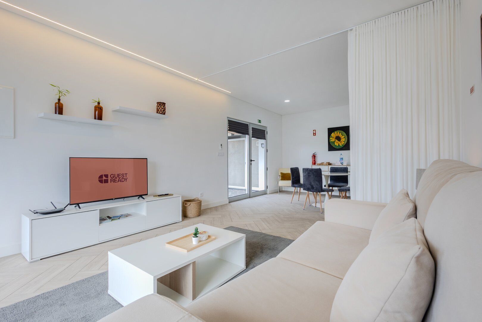 Ein modernes Wohnzimmer mit Flachbildfernseher, einer Couch, einem Couchtisch und einem Essbereich mit Stühlen und einem Tisch.