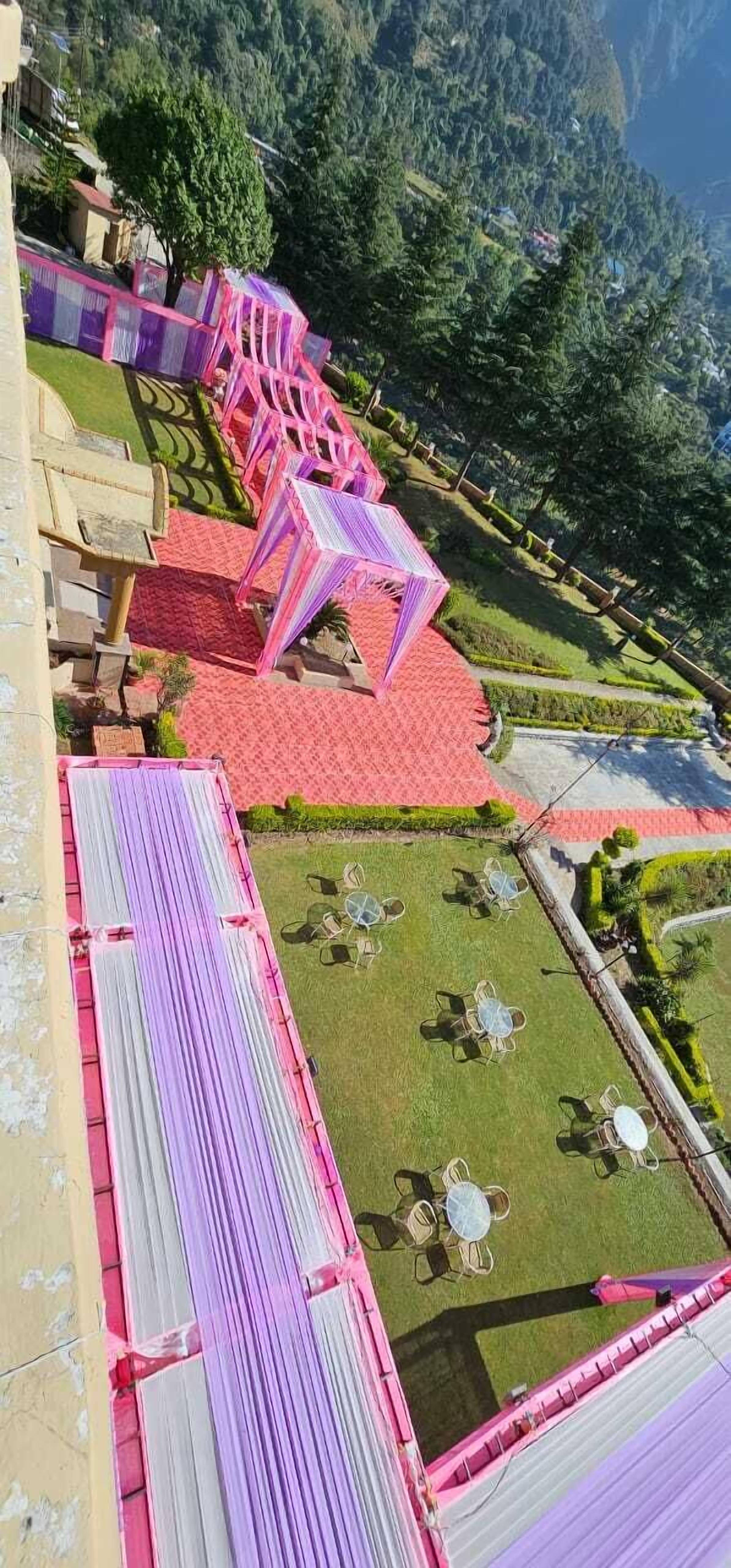 Un hotel con decorazioni nei toni del rosso e del rosa, area salotto esterna e vista sul paesaggio montuoso circostante.