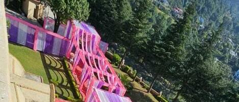 Un hotel con decorazioni nei toni del rosso e del rosa, area salotto esterna e vista sul paesaggio montuoso circostante.