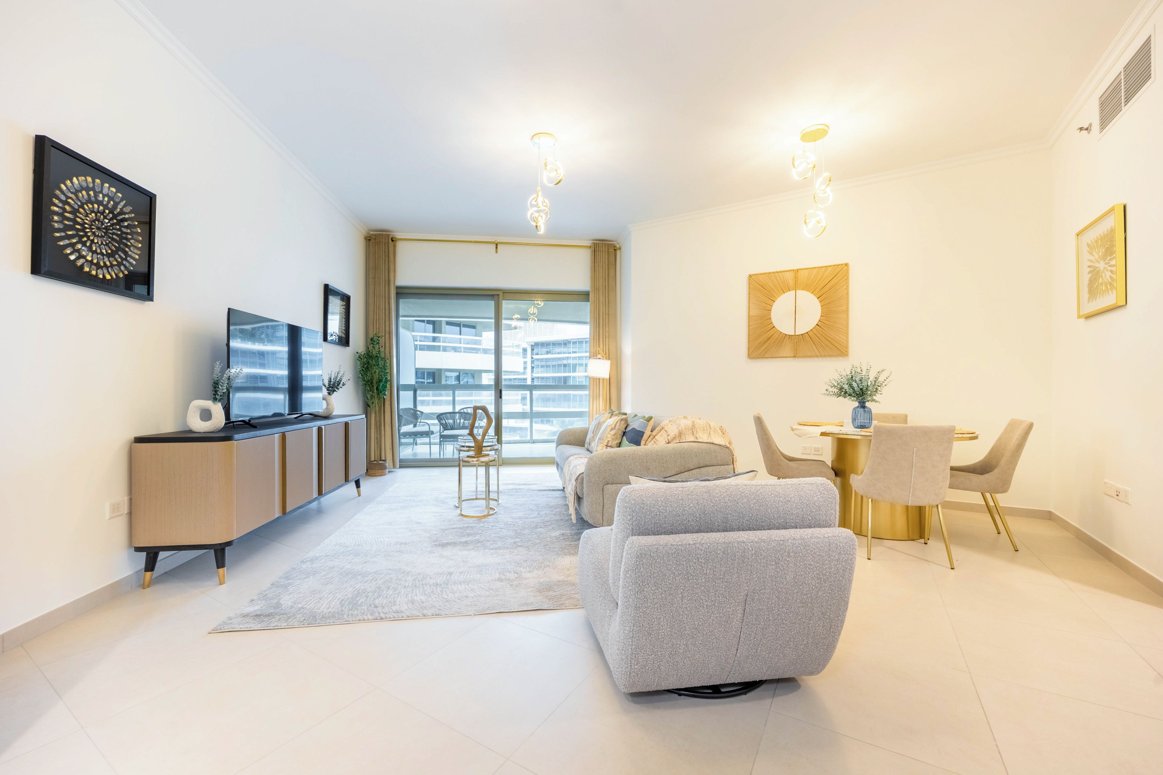 A modern living room with a sofa, a dining table with chairs, a TV on a cabinet, and artwork on the walls.