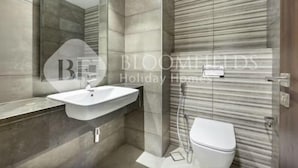 A modern bathroom with a large mirror, a sink, and a toilet. - 327 Bloomfields Magnificent 1BR Ajwan (Madinat Zayed)