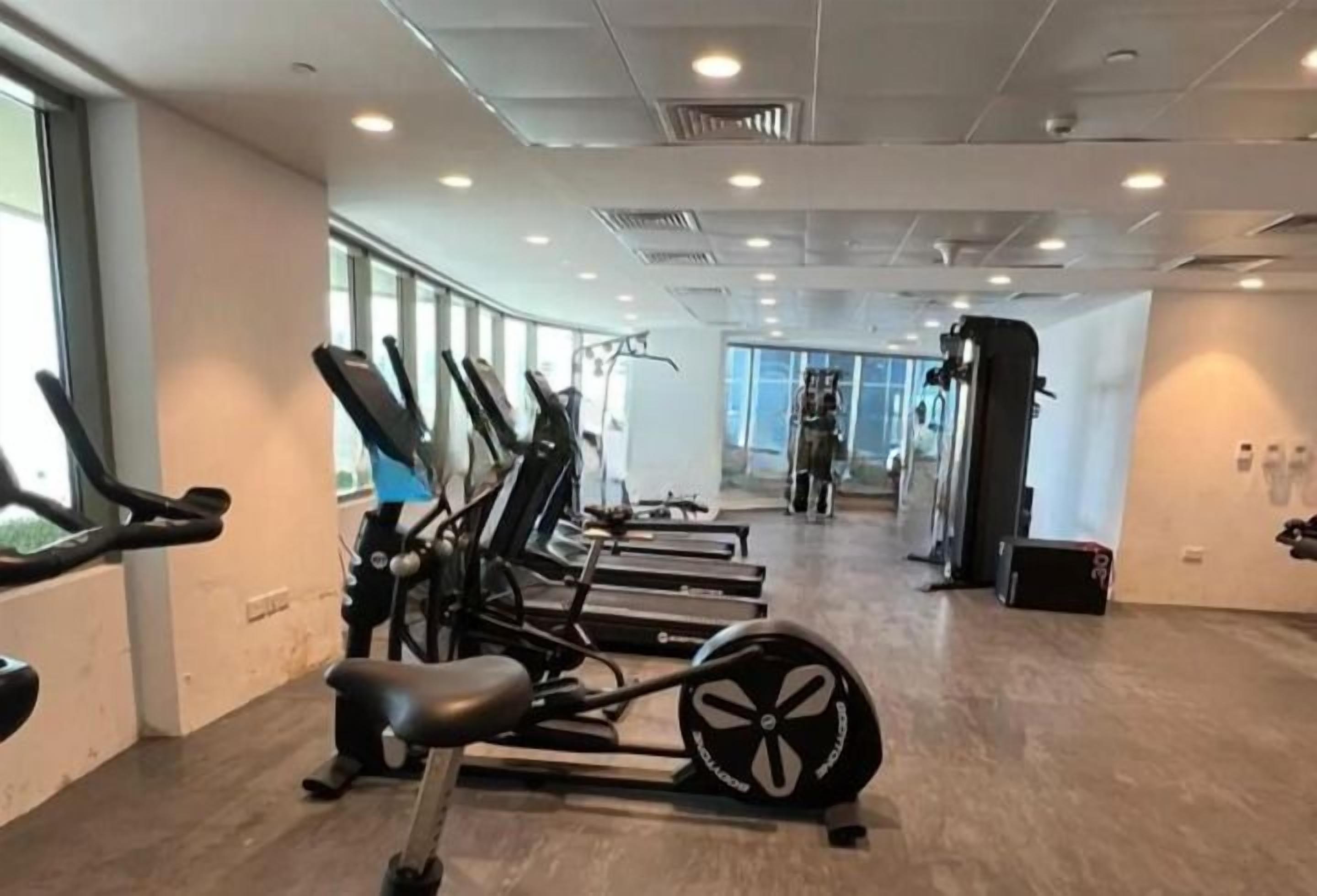 Un gimnasio con equipo de ejercicio, amplias ventanas y un interior moderno y limpio.