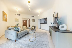 A modern living room with a grey sofa, a coffee table, and a kitchen visible in the background.