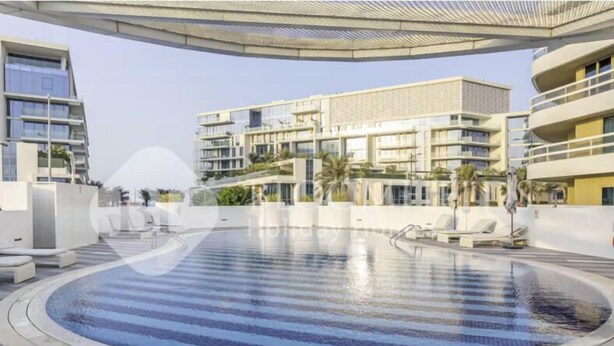 A modern hotel with a large outdoor swimming pool, multiple balconies, and a contemporary architectural design. - 327 Bloomfields Magnificent 1BR Ajwan (Madinat Zayed)